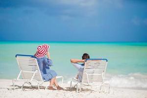 familia feliz relajándose en una playa tropical en las sillas de playa foto