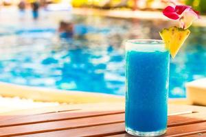Tropical blue cocktail on woodem table near swimming pool photo