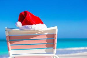 Red Santa hat on chair longue at tropical beach photo