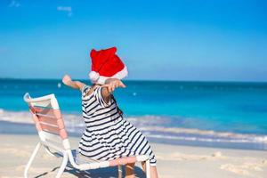 Little adorable girl wearing Santa hat at tropical beach photo