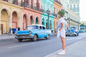 turista en zona popular cerca de el capitolio en la ciudad de la habana, cuba. retrato de niño fondo vintage coche americano clásico foto