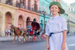 Adorable little girl in popular area in Old Havana, Cuba. Portrait of kid background vintage classic american car photo