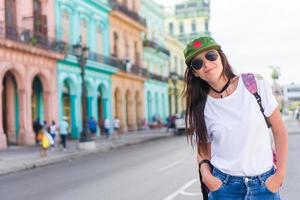 mujer joven en zona popular en la habana vieja, cuba. hermosa niña viajero fondo coloridas casas en la ciudad foto