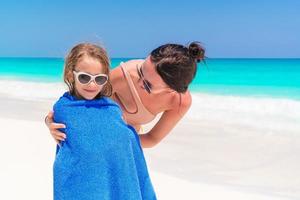 Happy family of mother and kid on the beach vacation. Little girl in towel on the seashore photo