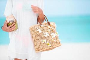 hermoso bolso con flores de frangipani y coco en manos femeninas foto