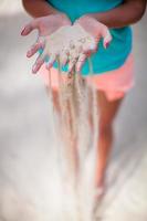 White sand through the fingers of the young girl photo