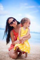 adorable niña y mamá feliz durante las vacaciones en la playa tropical foto