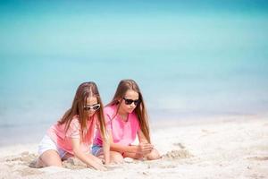 Two little happy girls have a lot of fun at tropical beach playing together photo
