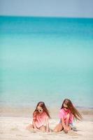 Two kids making sand castle and having fun at tropical beach photo