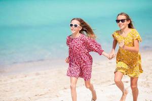 Little happy funny girls have a lot of fun at tropical beach playing together. Sunny day with rain in the sea photo