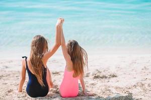 Little happy funny girls have a lot of fun at tropical beach playing together. photo