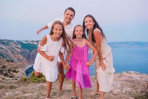 Happy family of four walking in the mountains on the sunset photo