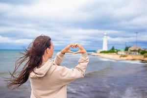 Woman walk to the lighthouse and make heart photo