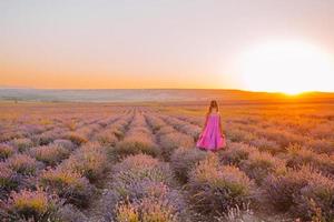 Woman in lavender flowers field at sunset in white dress and hat photo