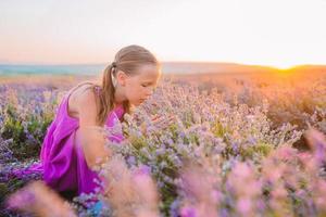 Woman in lavender flowers field at sunset in white dress and hat photo