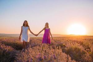 Kids in lavender flowers field at sunset in the dresses photo