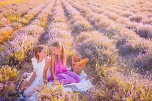 Kids in lavender flowers field at sunset in white dress and hat photo