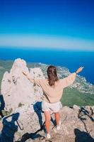 Tourist woman on edge of cliff background of seashore photo