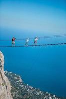 Family crossing the chasm on the rope bridge. Black sea background, Crimea, Russia photo