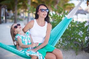 Young mommy and little girl on tropical vacation relaxing in hammock photo