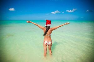 Back view of beautiful girl in santa hat walking like a bird photo