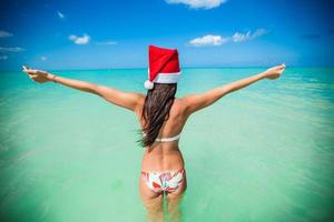 vista trasera de una hermosa chica con sombrero de santa caminando como un pájaro foto