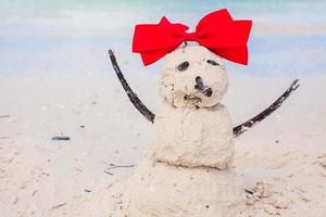 Little sandy snowman with bow on white Caribbean beach photo