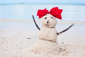 Little sandy snowman with bow on white Caribbean beach photo