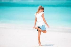 Adorable little girl have fun at tropical beach during vacation photo