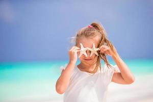 Adorable little girl with starfish on the beach photo