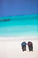 Summer black flip flops with sunglasses background turquoise sea photo