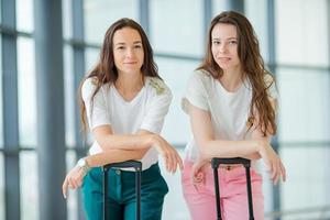 mujeres jóvenes con equipaje en el aeropuerto internacional caminando con su equipaje. Pasajeros de líneas aéreas en un salón del aeropuerto esperando aviones de vuelo foto