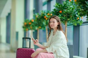 Portrait of young woman with smartphone in international airport. Airline passenger in an airport lounge waiting for flight aircraft photo