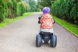 Back view of adorable little girls ride a motorbike in green park photo