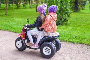 Little adorable sisters sitting on bike in green park photo