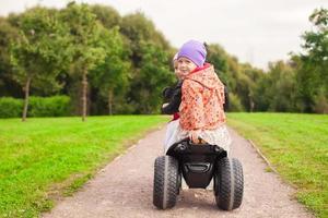 Happy little cute girls ride a motorbike outside photo