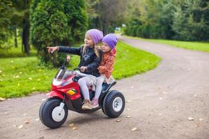 Adorable little girls riding on motobike in the green park photo