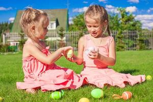 Adorable little girls playing with Easter Eggs on green grass photo