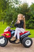 adorable niña divirtiéndose en su motocicleta de juguete foto