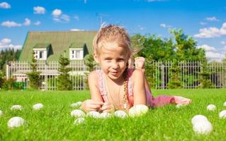 Portrait of little adorable girl playing with white Easter eggs in the yard photo