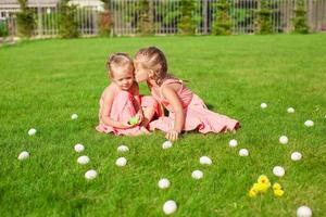 Older sister kissing younger on a green glade of Easter Eggs photo