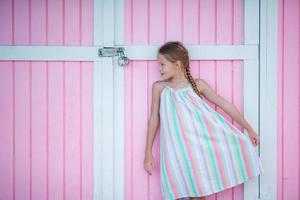 Little cute girl standing near bright colored wall photo