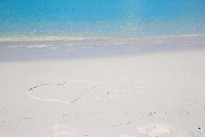 amor escrito en la arena blanca de la playa tropical foto