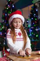 Adorable little girl baking gingerbread cookies for Christmas photo