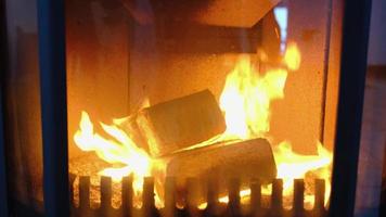 Brennstoffbriketts aus gepresstem Sägemehl zum Anzünden des Ofens - sparsamer alternativer umweltfreundlicher Brennstoff für den Kamin im Haus. Brennholz brennt im Ofen im Innenraum video