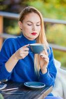 concepto de otoño - hermosa mujer bebiendo café en el parque de otoño bajo el follaje de otoño foto