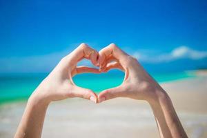 Close up of heart made by female hands background the turquoise ocean photo