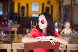 Young woman having breakfast at outdoor cafe on summer vacation photo