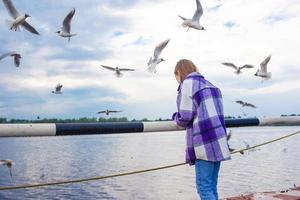 Cute little girl feed seagulls photo