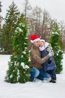 Happy family in Santa hats with christmas tree outdoor photo